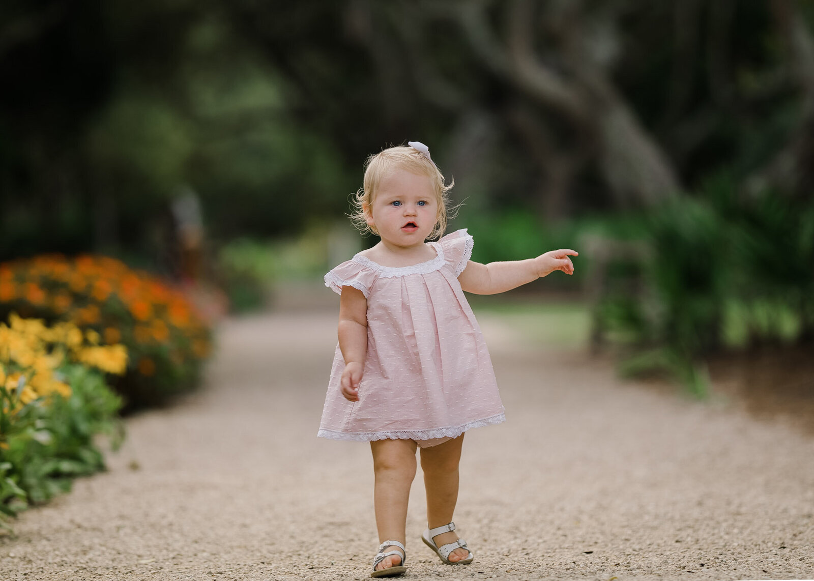 A toddler girl in a pink dress walks through a gravel garden path charlotte nc toy stores